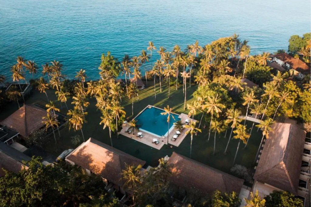 Aerial view of Alila Manggis, a luxury oceanfront resort nestled along the coastline of East Bali, surrounded by lush greenery and the turquoise sea.